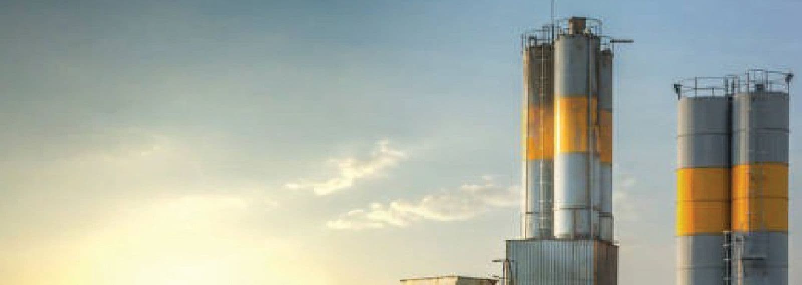 Cement plant silos and industrial facility at sunset